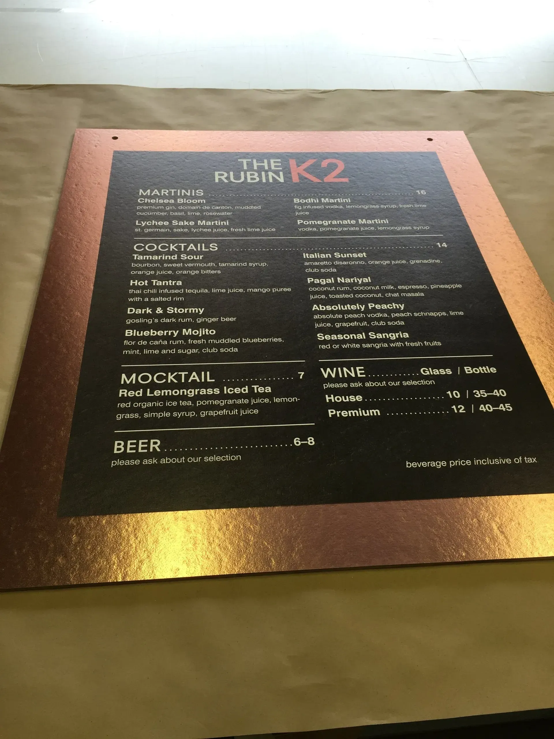 Close-up of a black drink menu on a gold tabletop, titled “The Running K2.”