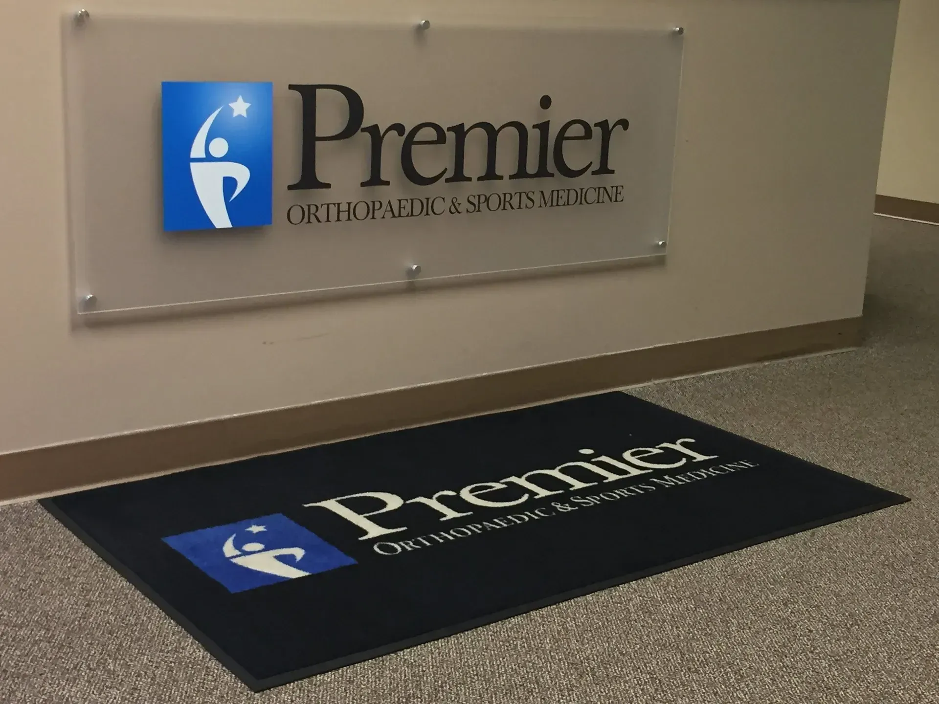 Premier Orthopedic Specialists sign and matching floor mat in a clinic lobby.