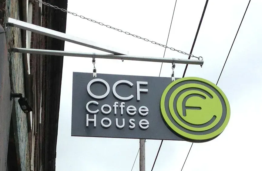 OCF Coffee House sign with black and green circular logo on a building exterior