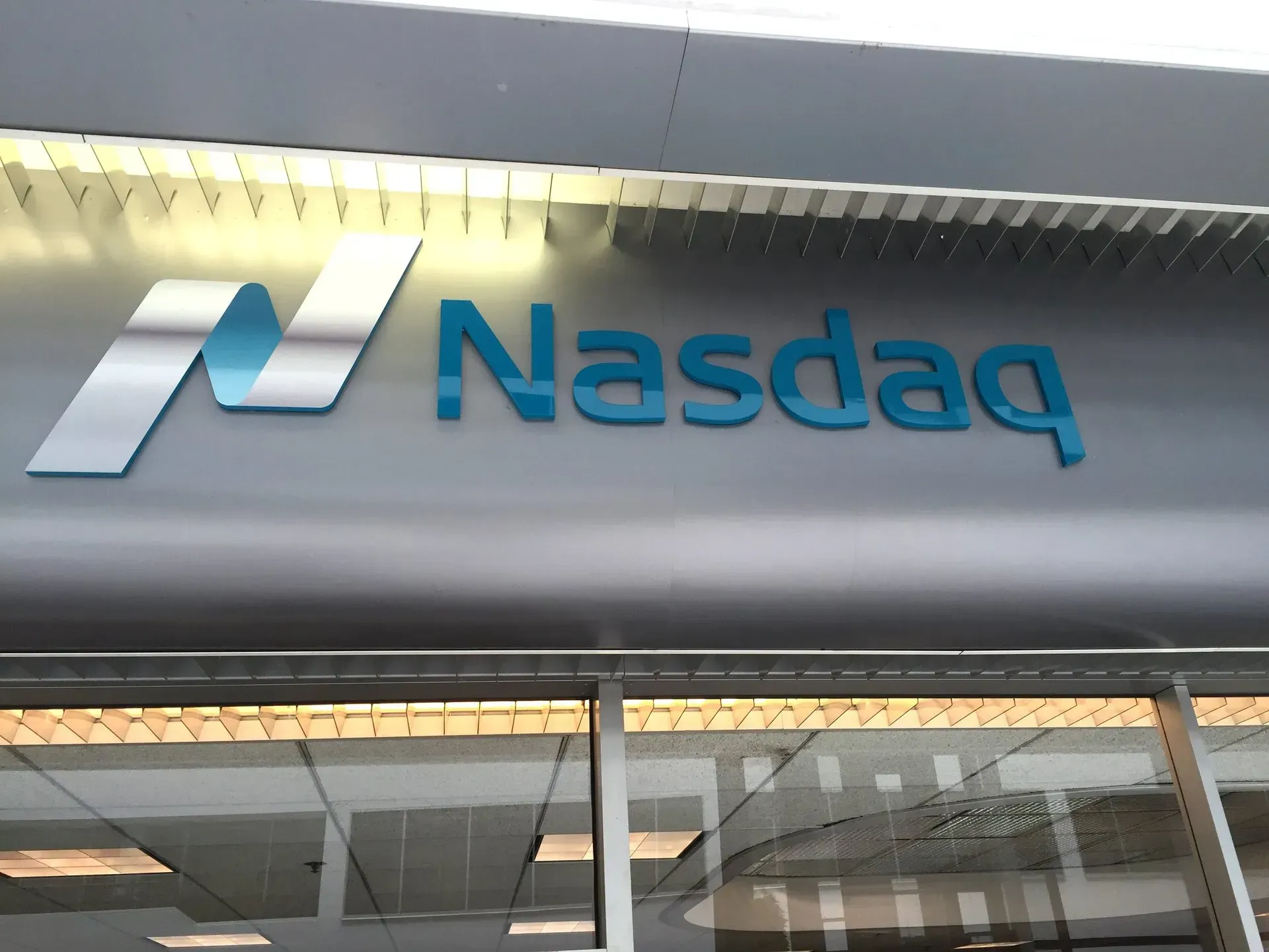 Nasdaq sign on a building entrance with blue logo and lettering