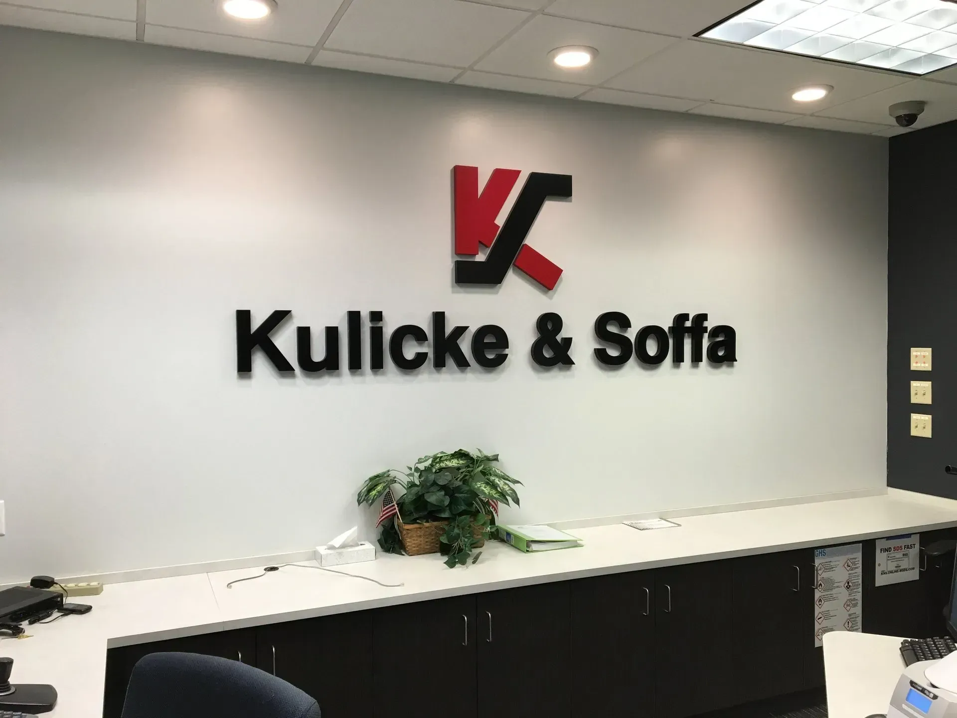 Kulicke & Soffa lobby wall logo above a reception counter with a plant underneath