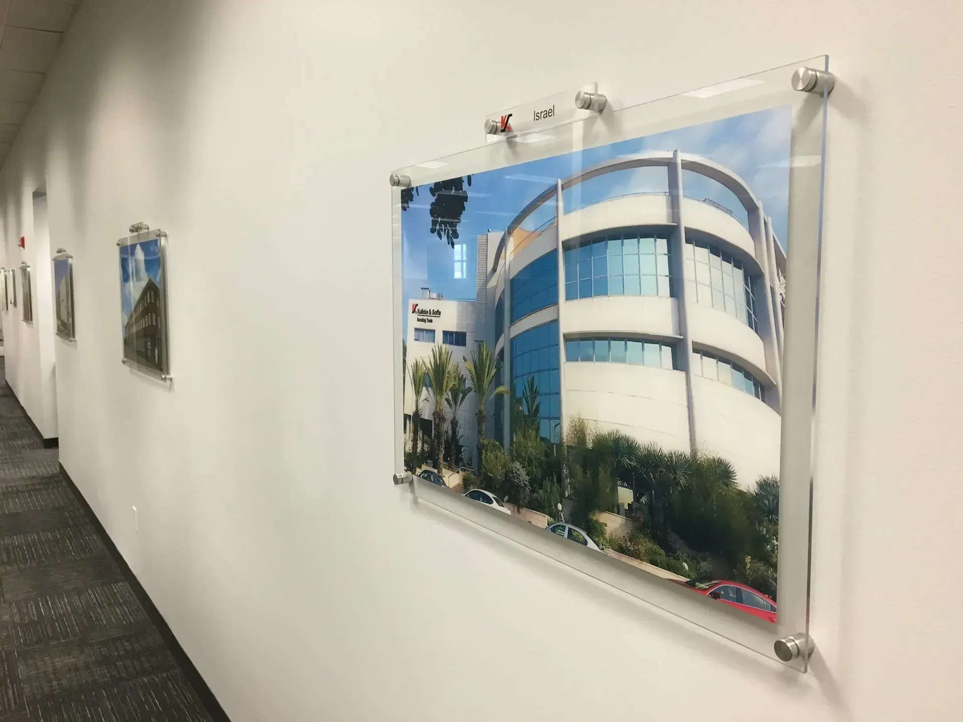Hallway with framed photos on a white wall, including a large photo of a blue-and-white building