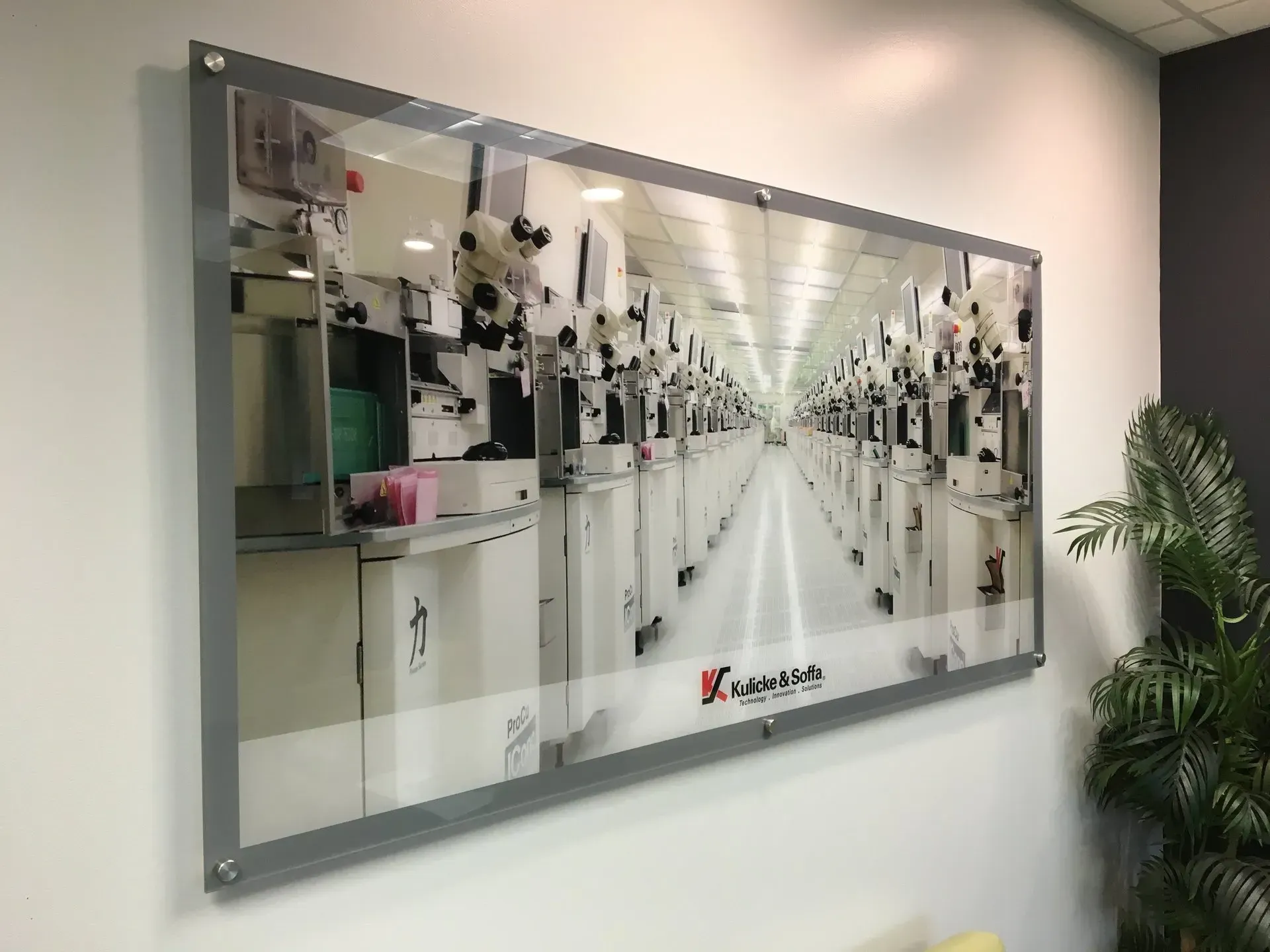 Framed photo of a bright industrial corridor with repeating machines and a long vanishing-point perspective