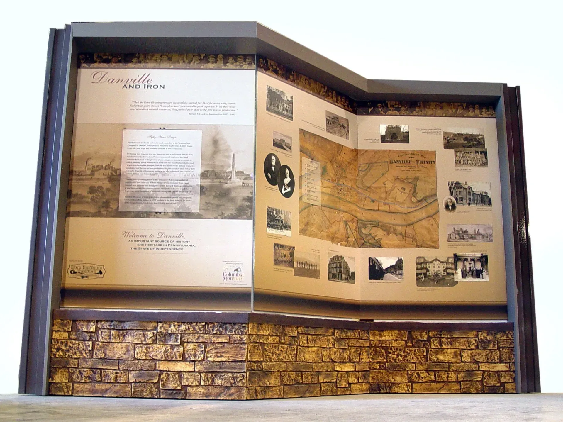 Museum-style display case with historical documents, maps, and framed photos on a wood-paneled exhibit wall