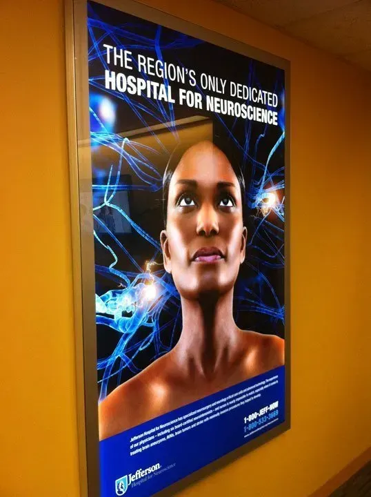 Hospital poster with a woman's face and blue neural graphics, reading “The region’s only dedicated hospital for neurosciences.”