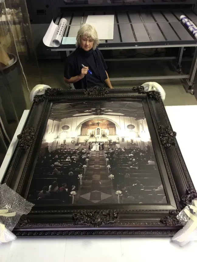 Person working beside a large framed painting on a workshop table