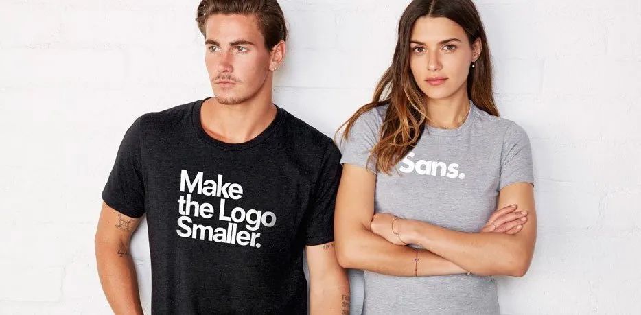 Two models wearing slogan T-shirts, one black and one gray, standing against a white background