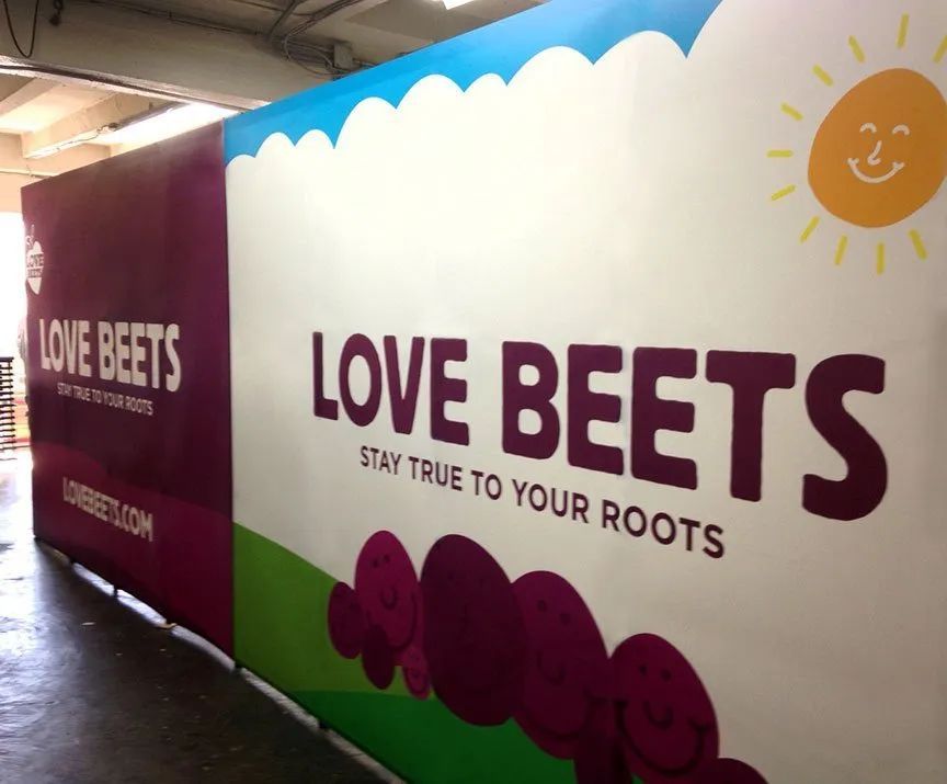 “LOVE BEETS” wall mural in a hallway, with purple beet graphics and a smiling sun icon.