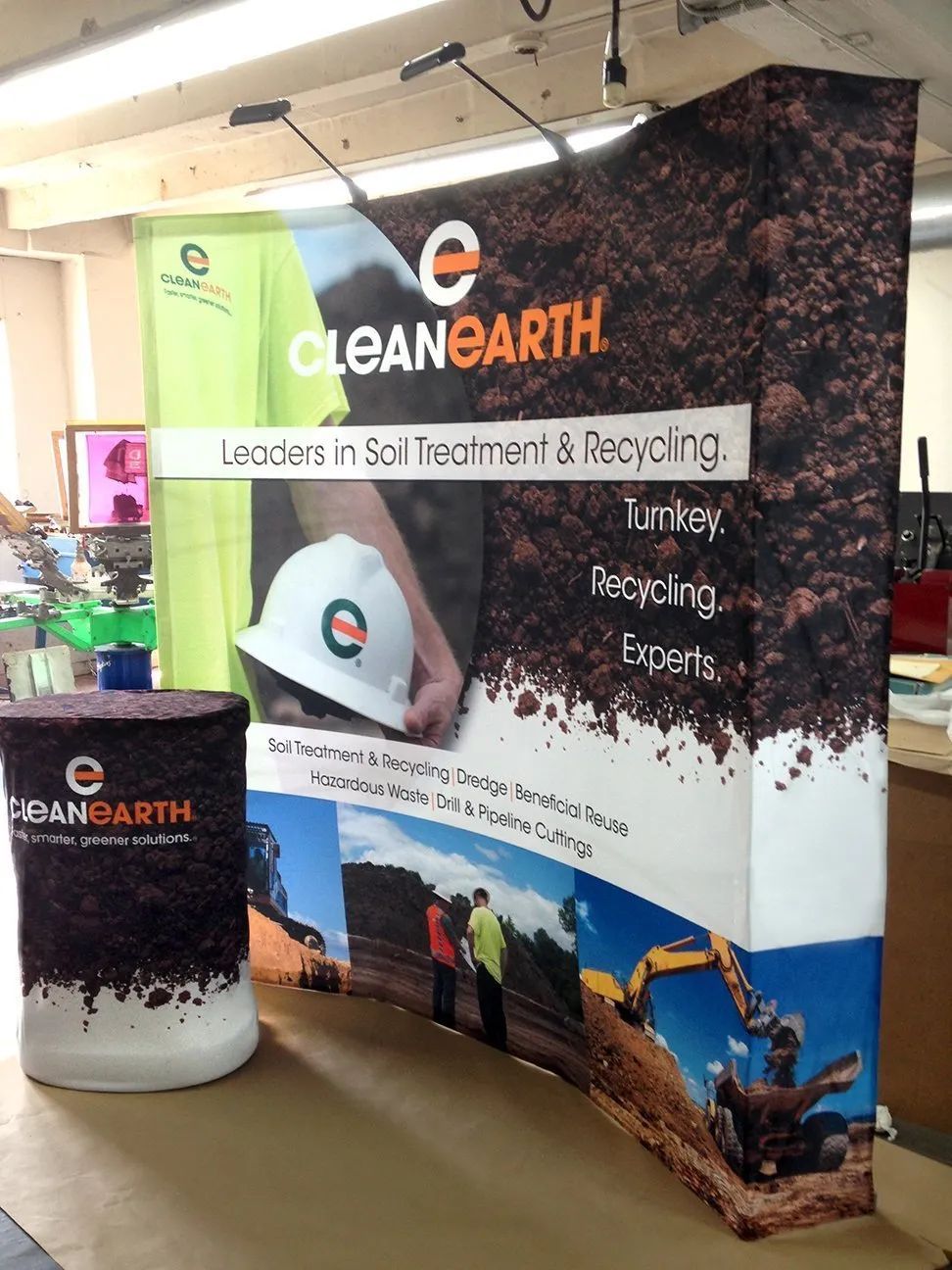Clean Earth trade show booth with green-and-black banner and branded counter display