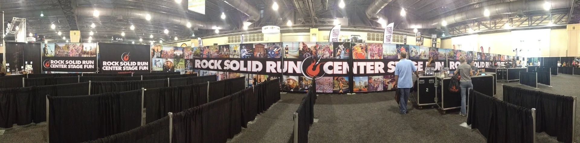 Wide indoor arena with black barriers, bright lights, and a banner reading “Rock Solid Run C