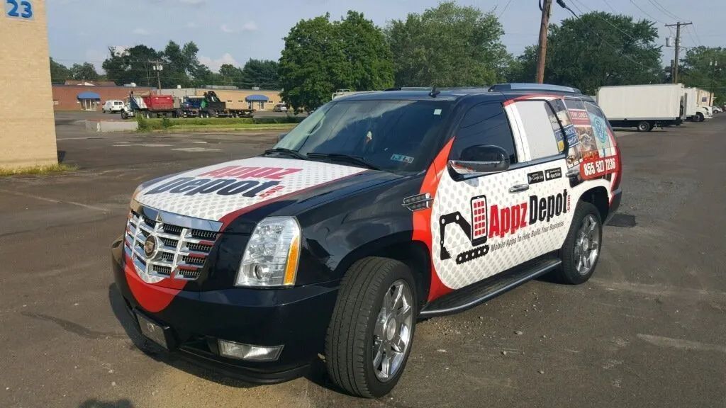 Branded black SUV with red-and-white graphics parked in a lot on a sunny day