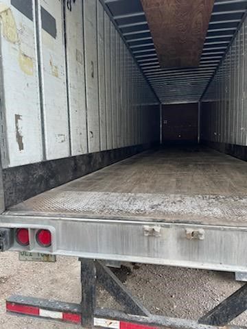 Open rear doors of an empty semi-truck trailer showing the interior floor and corrugated side walls.