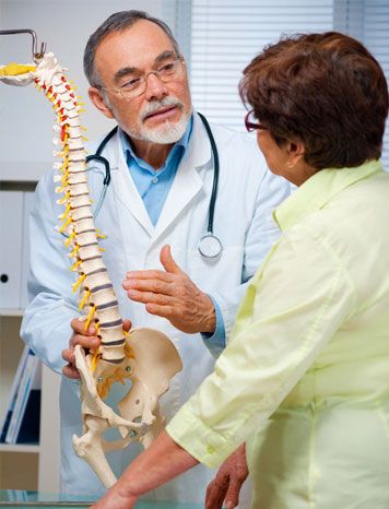 Chiropractor showing his patient an anatomic spine