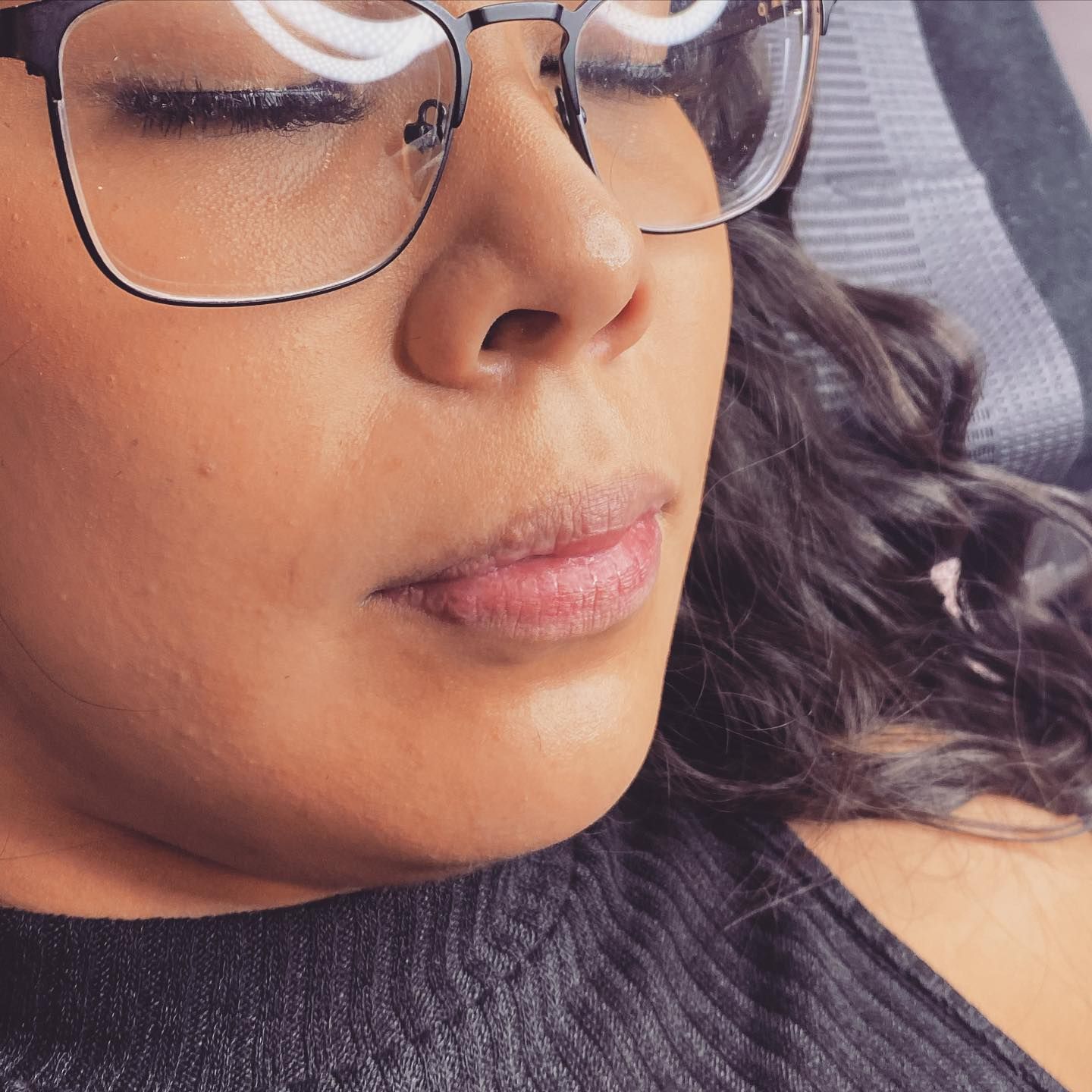 A close-up view of a person with their eyes closed, wearing glasses, and lying down.