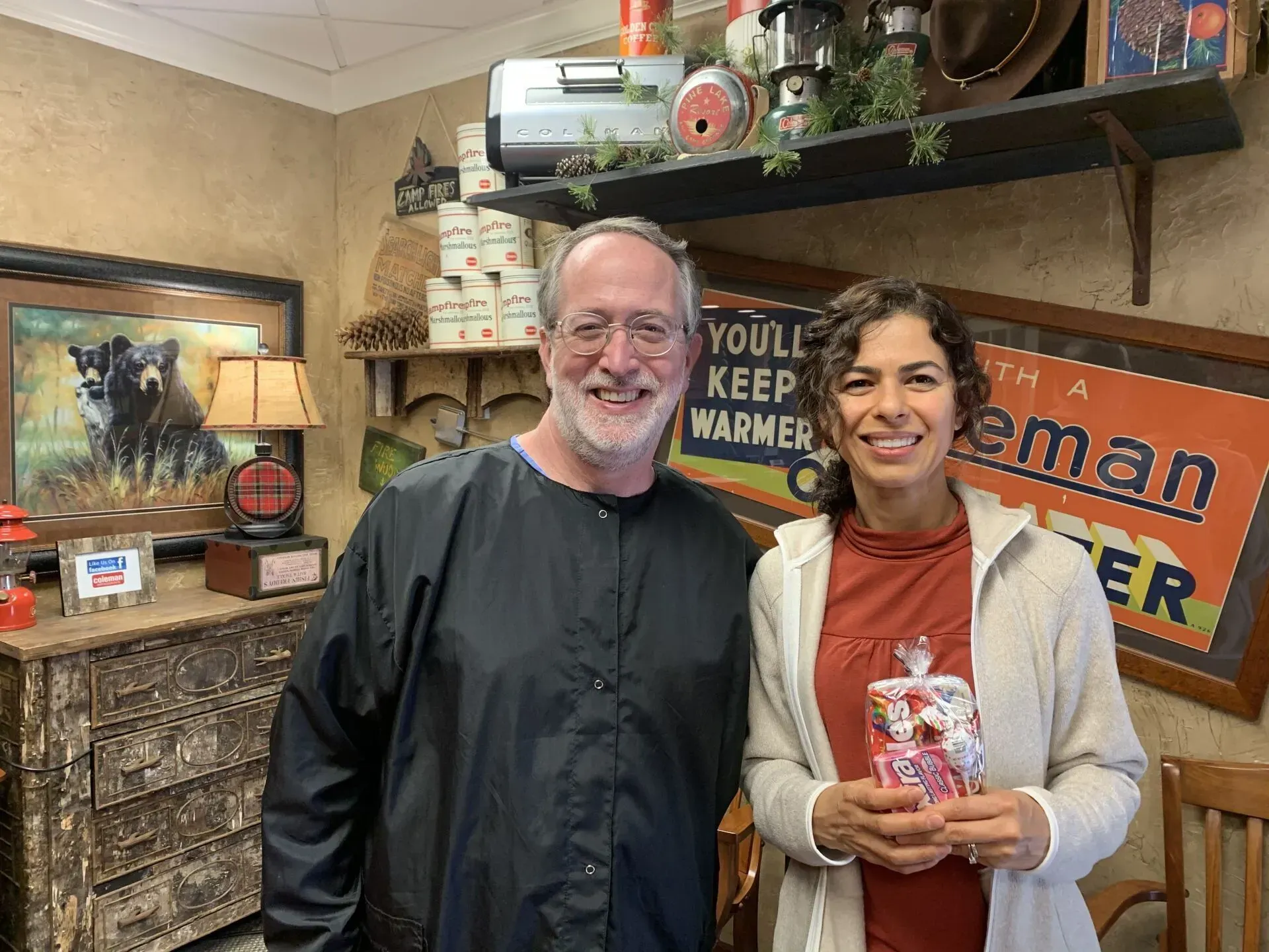 Two people pose inside a rustic-themed store. The woman holds a gift.