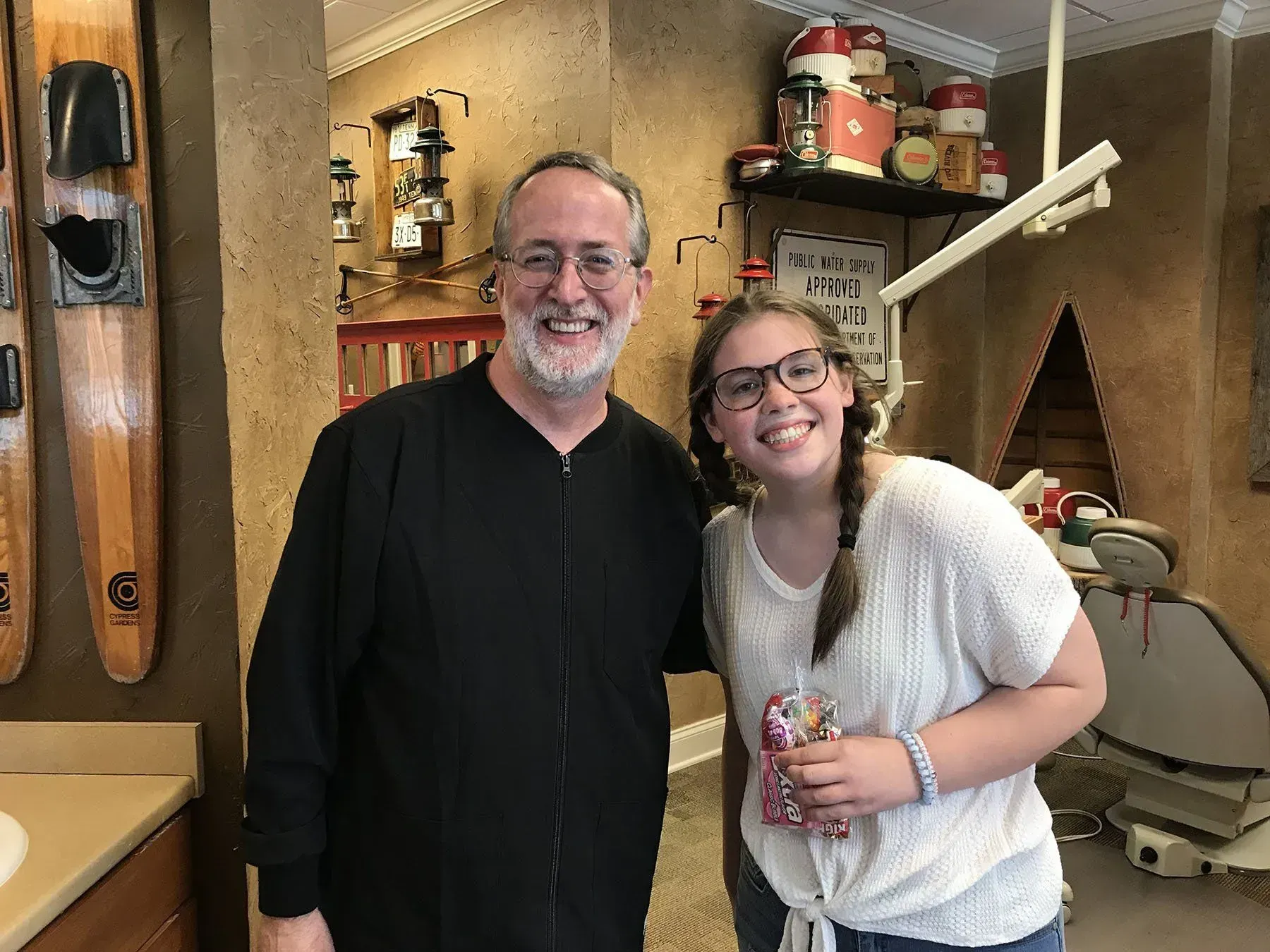 Dentist and patient smiling together in a dental office. The setting is decorated, appearing playful.