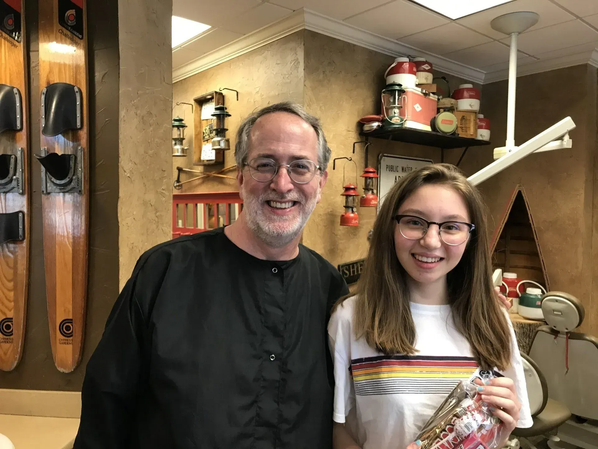 Man and young person smiling next to each other in a shop. The person on the right is holding a gift.