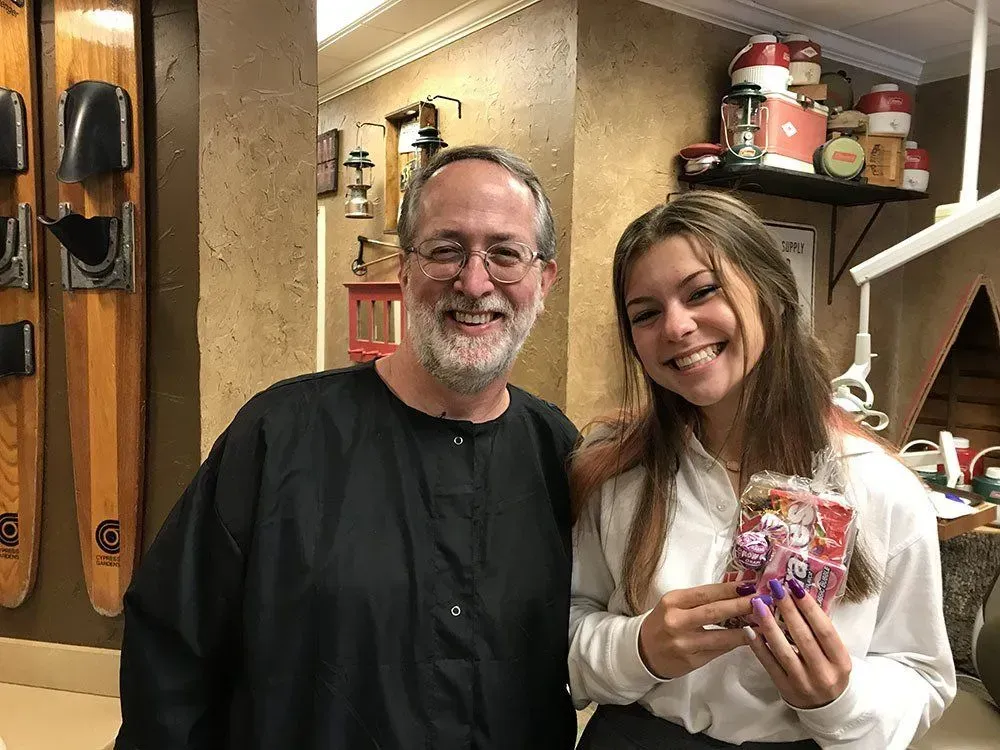 Man and young person smiling, holding a gift bag, inside a shop.