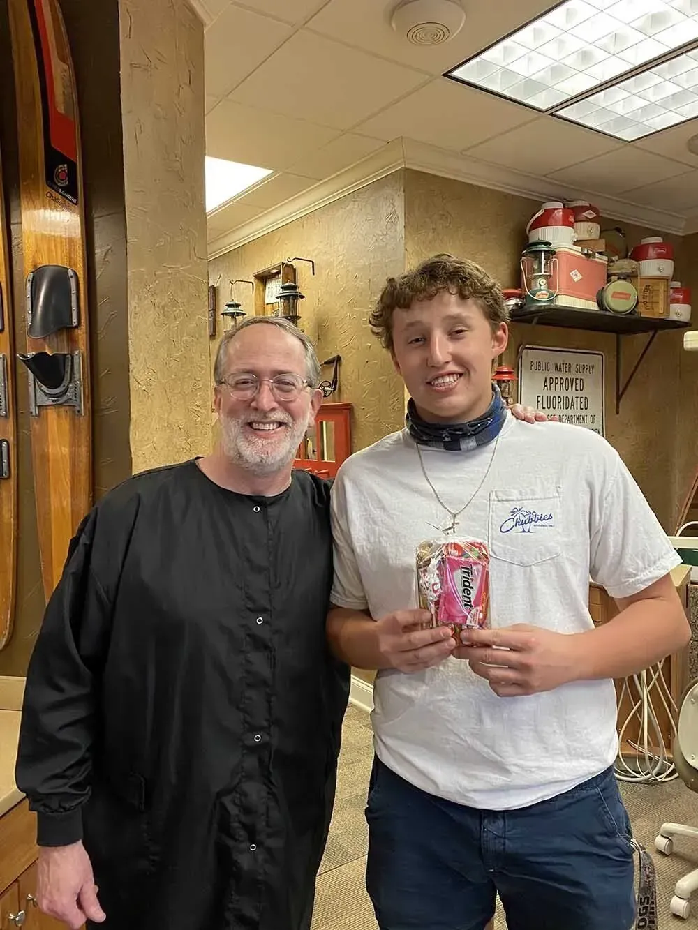 Man and young person in a shop, man holds a gift, both smile. The shop has sports equipment.