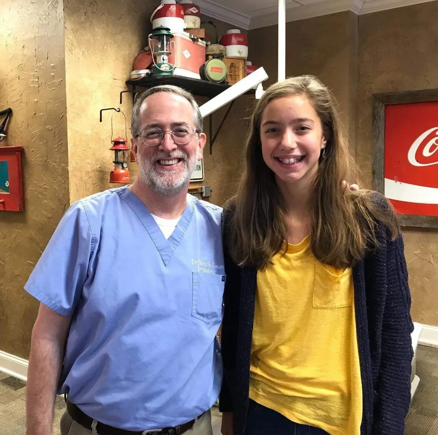 Man in scrubs and young person smiling together in a room with vintage decor.