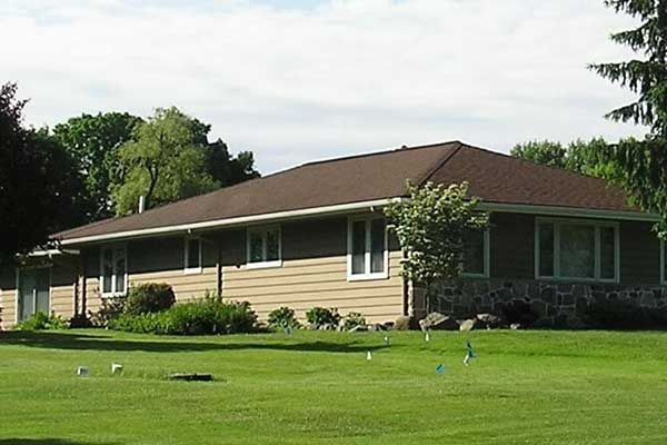 A house sits in the middle of a lush green field