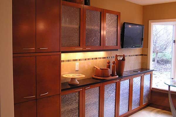 A kitchen with wooden cabinets and a flat screen tv