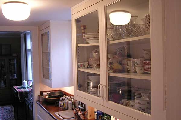 A kitchen with white cabinets and glass doors filled with dishes
