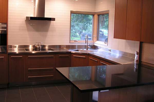 A kitchen with stainless steel counter tops and wooden cabinets