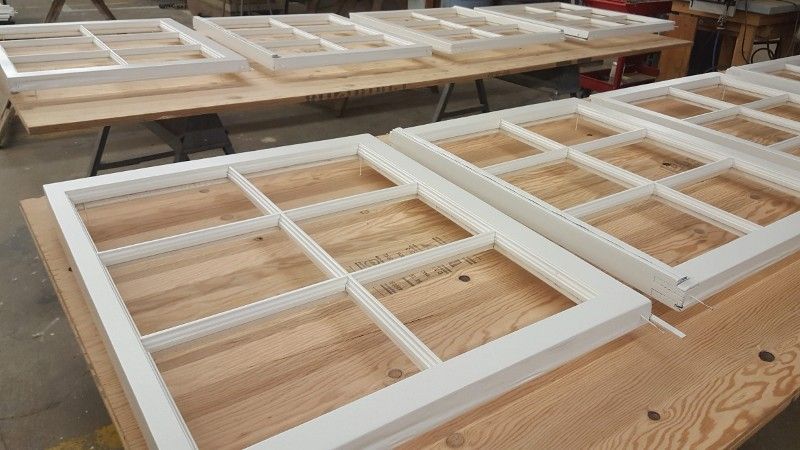 A bunch of white windows are sitting on top of a wooden table.