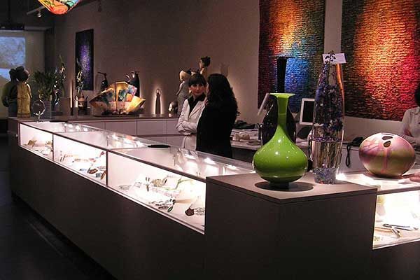 A woman is standing at a counter in a store with a green vase on it