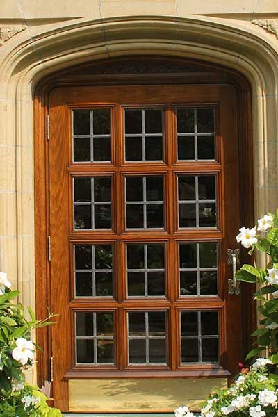 A wooden door with lots of windows and flowers in front of it