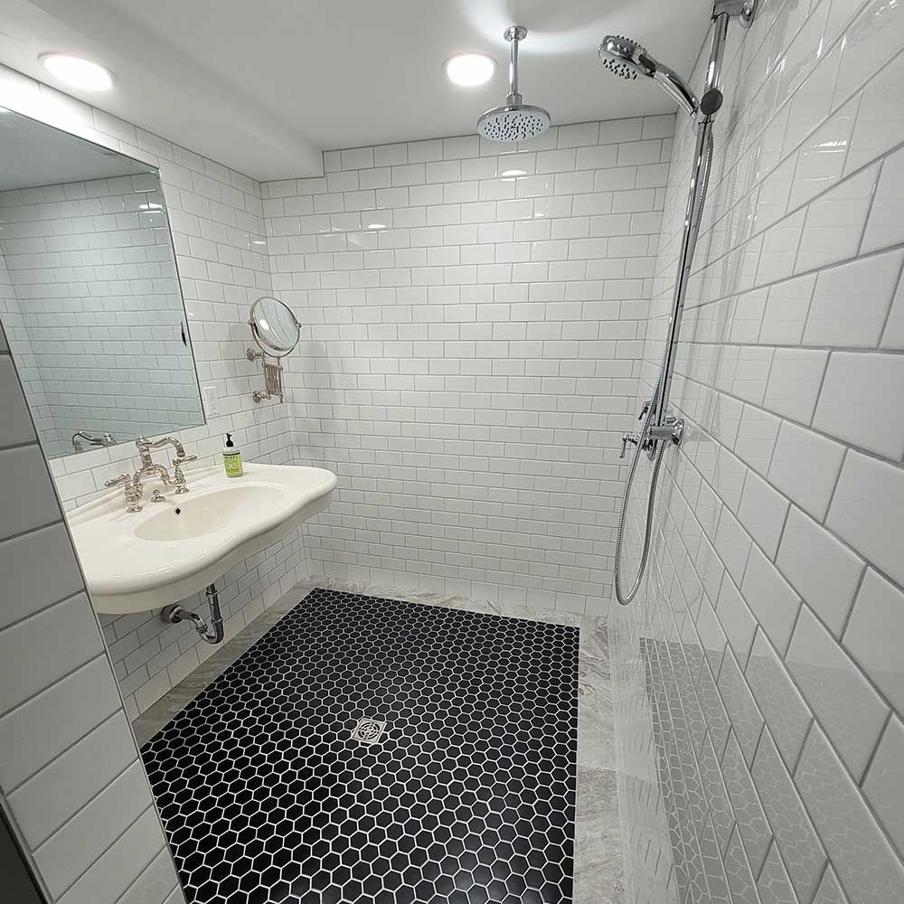 A bathroom with white tiles and a black tile floor