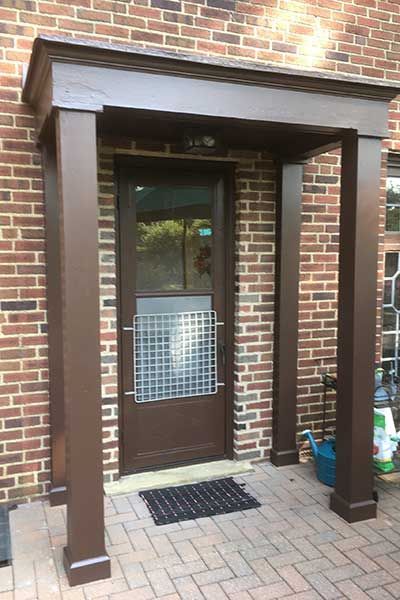 A brick building with a brown door and a porch.