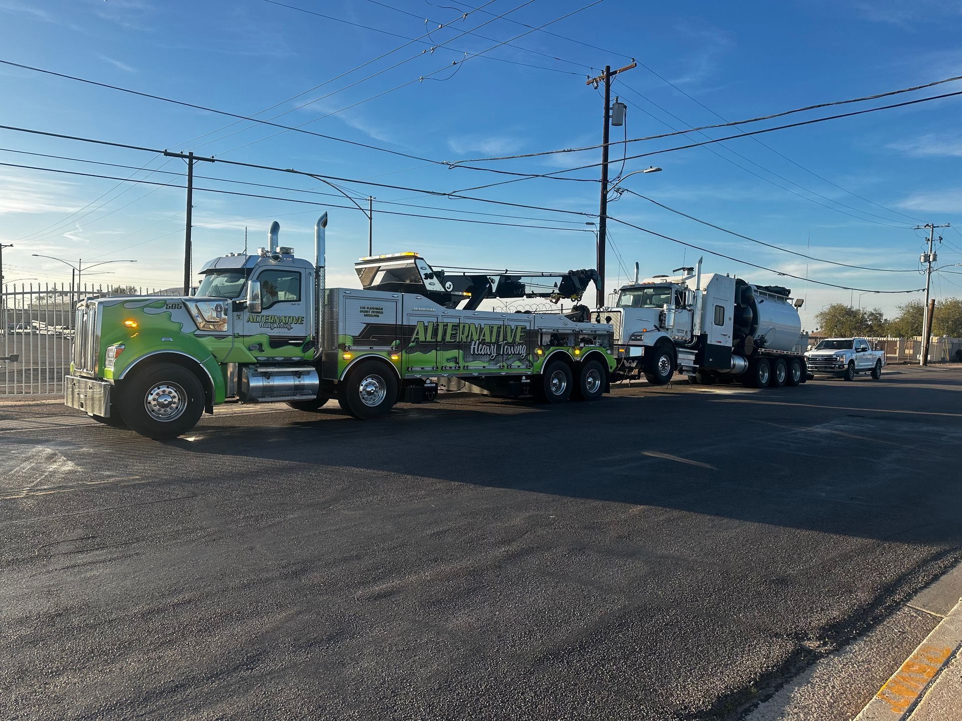 A row of tow trucks are parked on the side of the road.