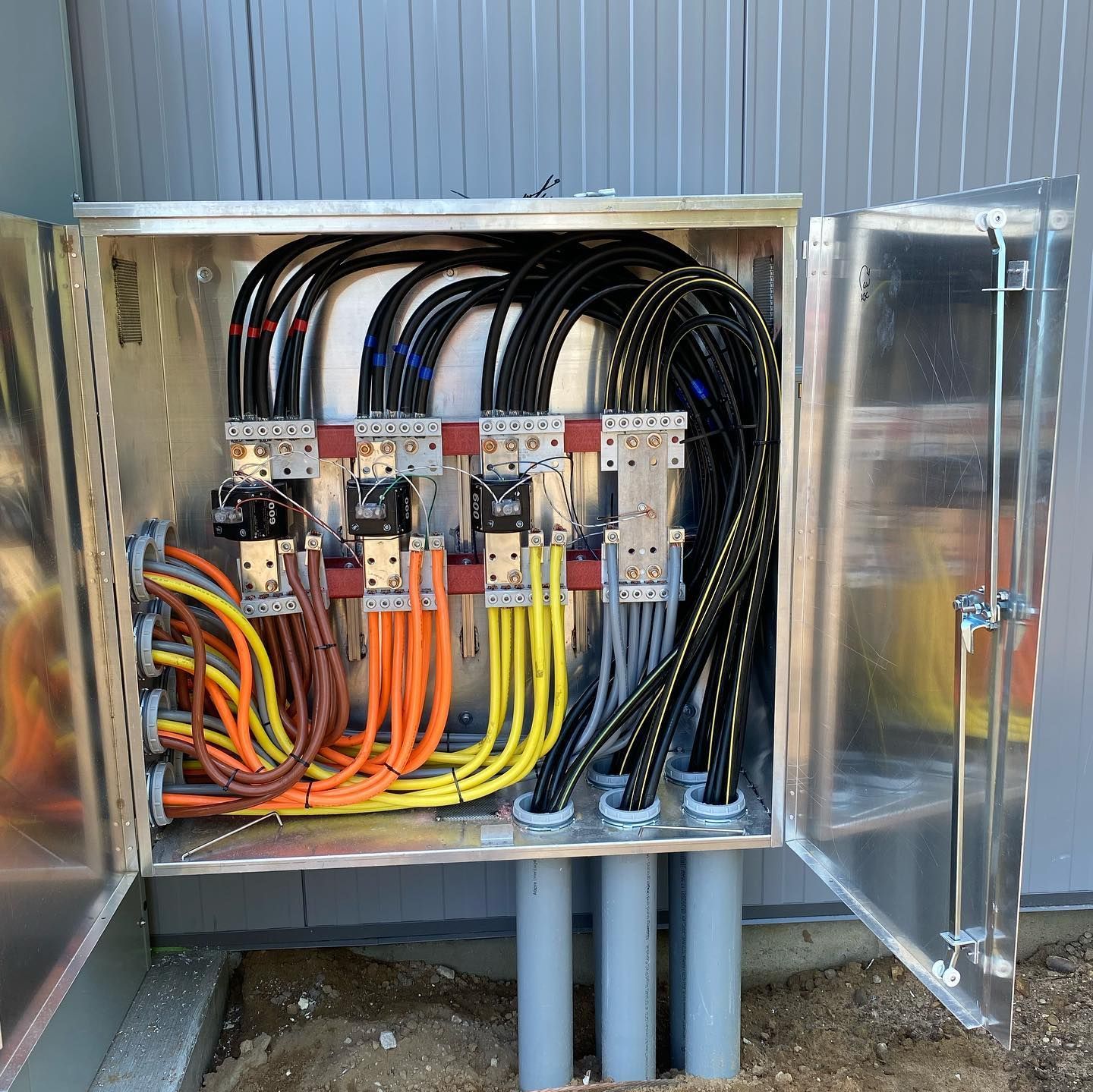 Open electrical panel with colored wires and conduit, mounted outside.