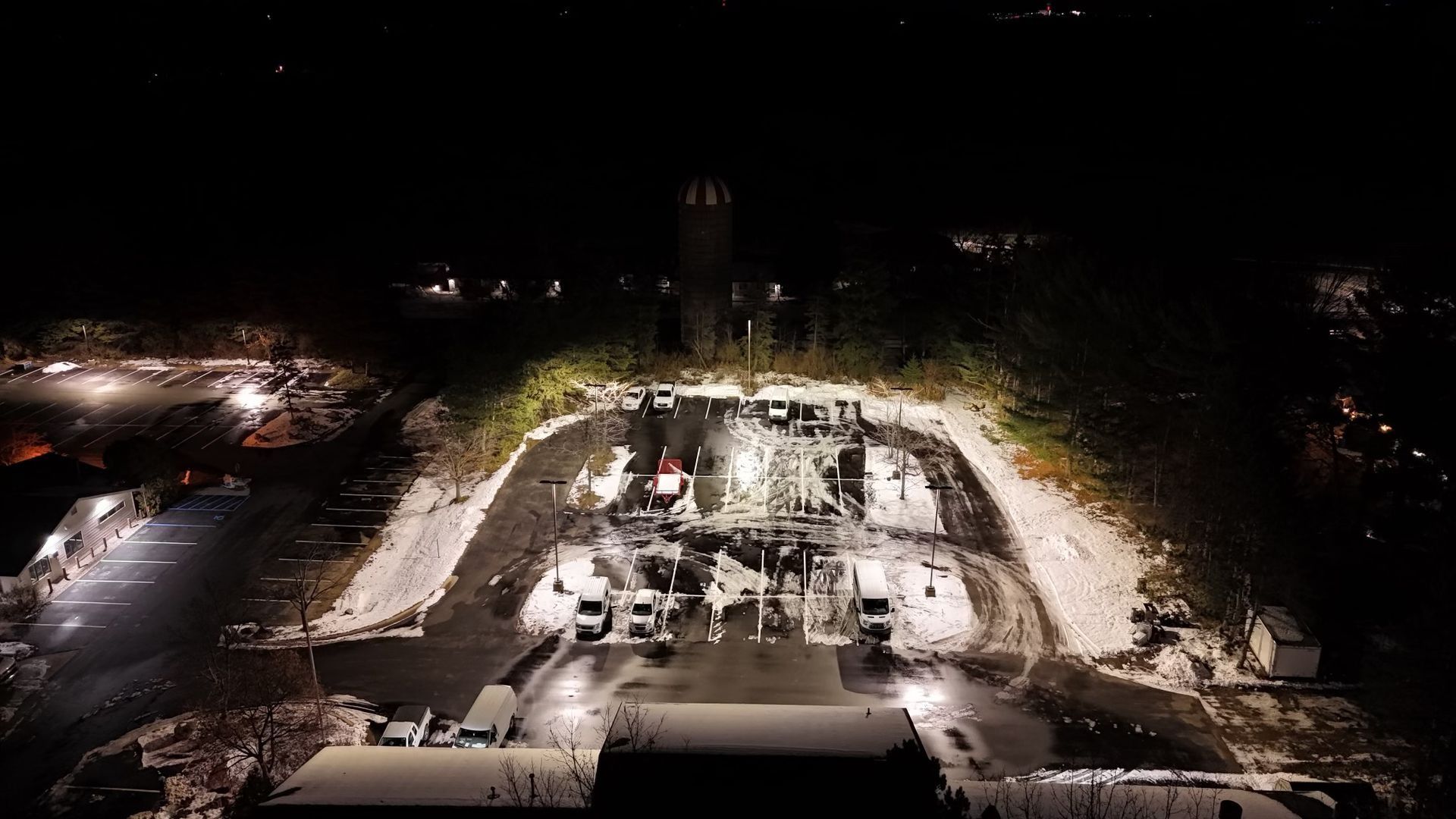 Nighttime aerial view of construction site with lights and tower in the background.