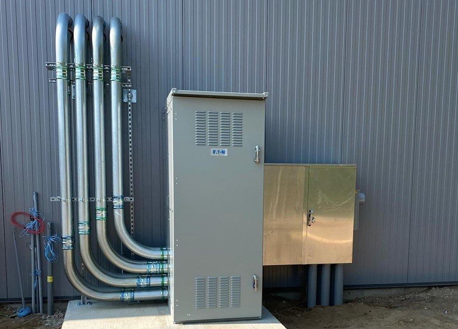 Electrical transformer and conduit attached to a metal building.