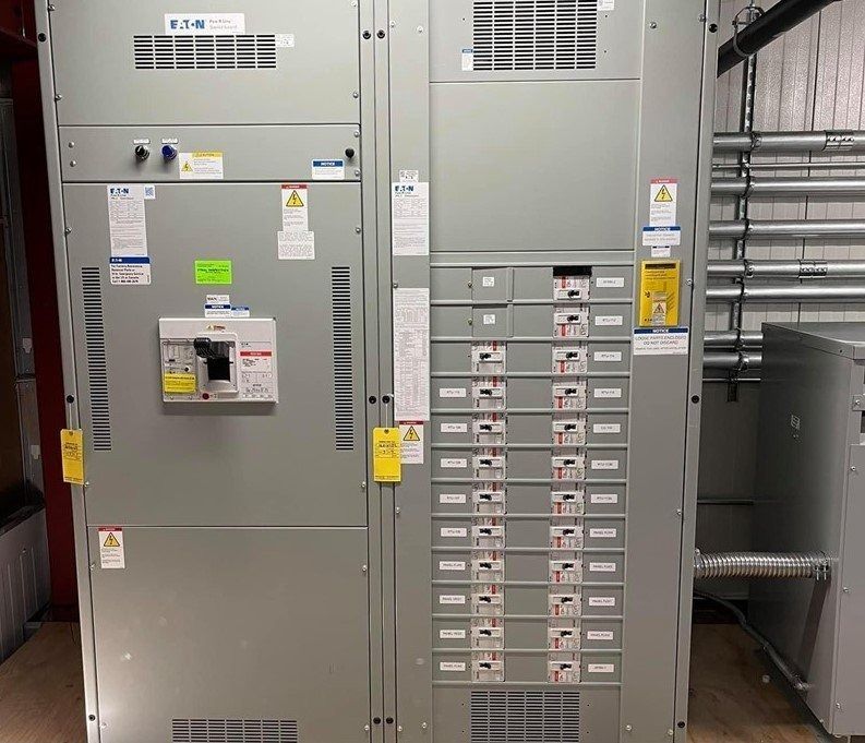 Electrical distribution panel with circuit breakers, labels, and safety warnings.