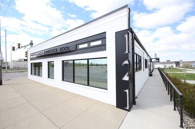 Modern white-and-black commercial building with large windows and a sidewalk corner entrance
