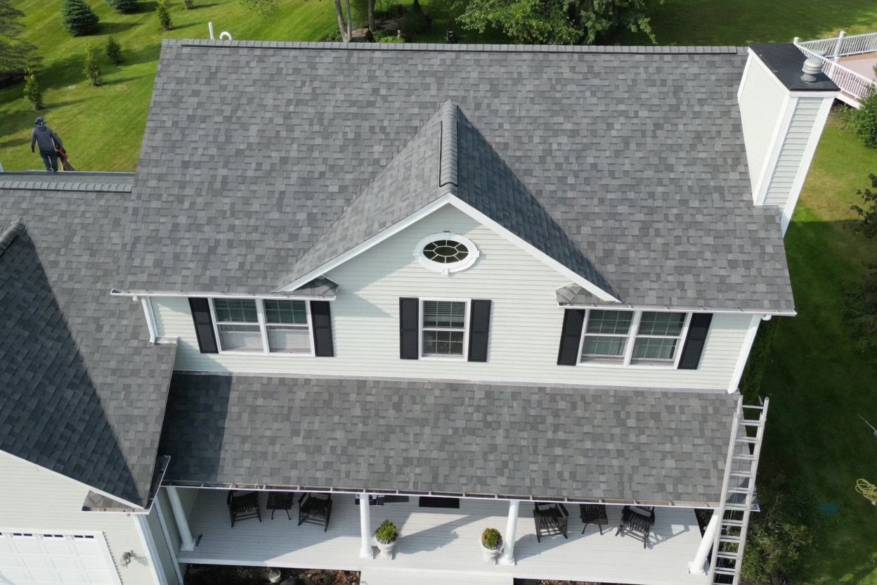 Aerial view of a gray-roofed two-story house with white siding and a front porch.