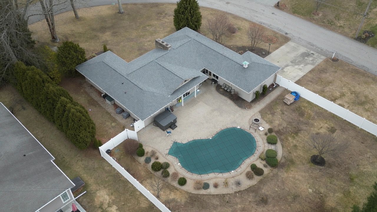 Aerial view of a house with a backyard swimming pool and fenced yard.