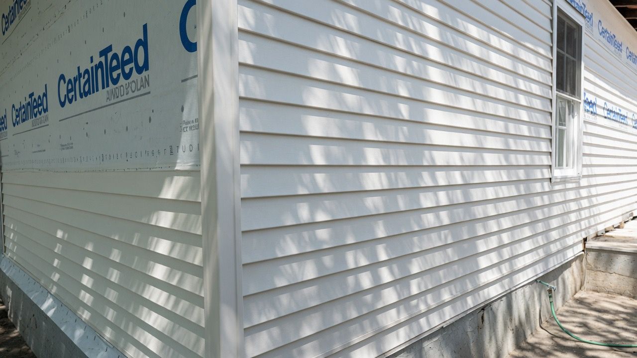 White corrugated exterior wall with blue lettering on a building under construction in bright sunlight