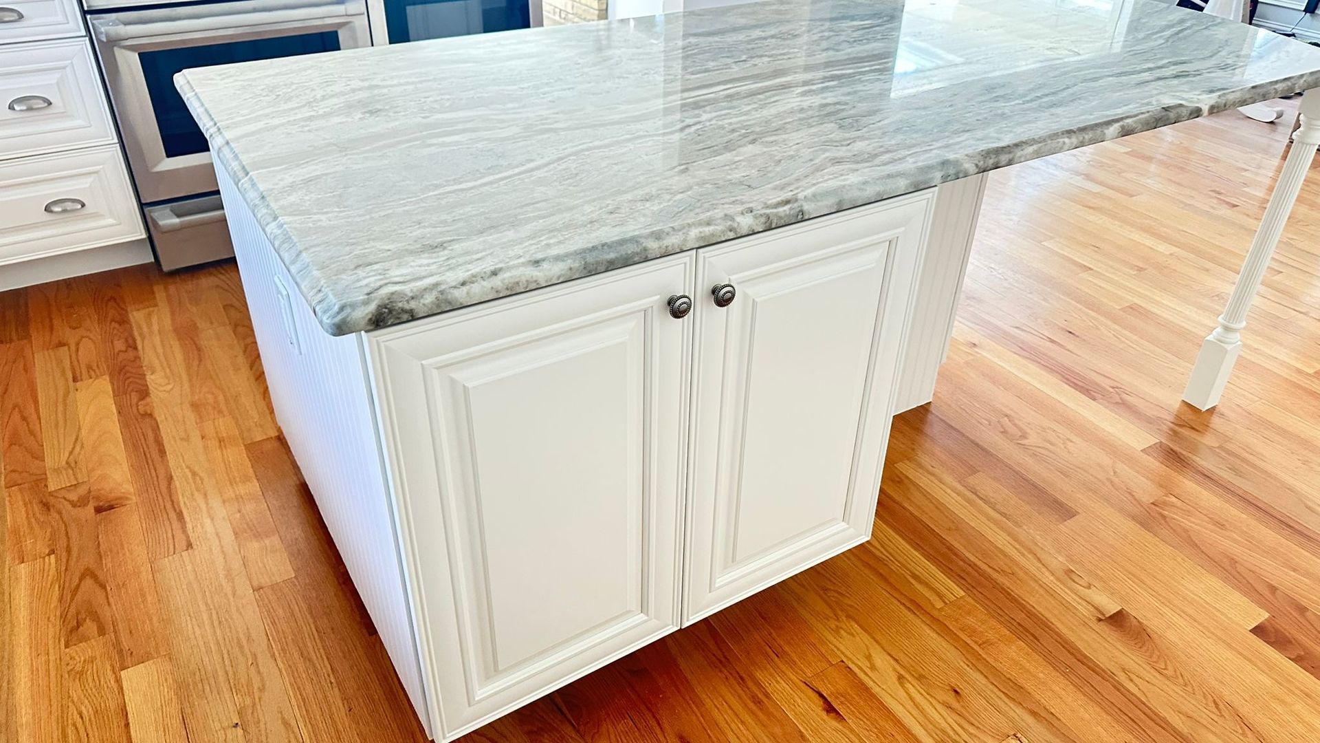 White kitchen island with granite countertop on hardwood floor