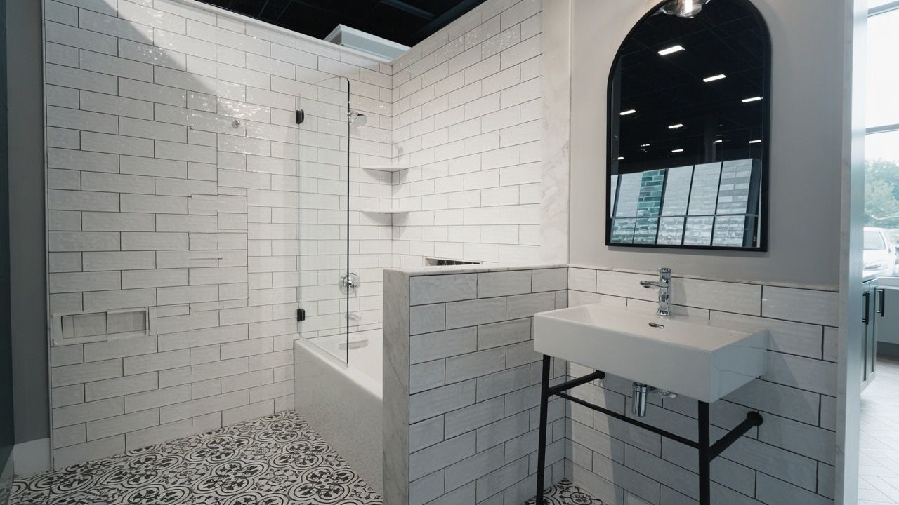 Modern white-tiled bathroom with shower, sink, mirror, and pebble floor