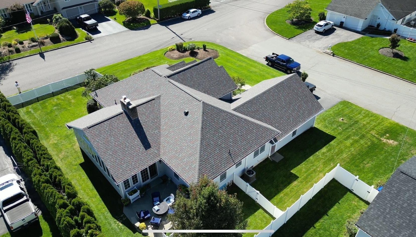 Aerial view of a suburban house with gray roof, green lawn, and surrounding streets.