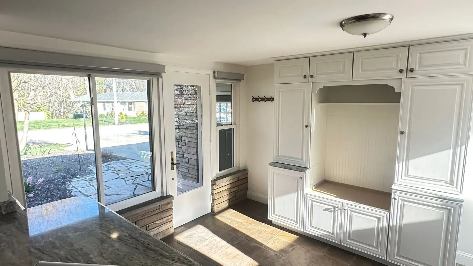 Bright living room with sliding glass door, large built-in white cabinets, and sunlight on the floor