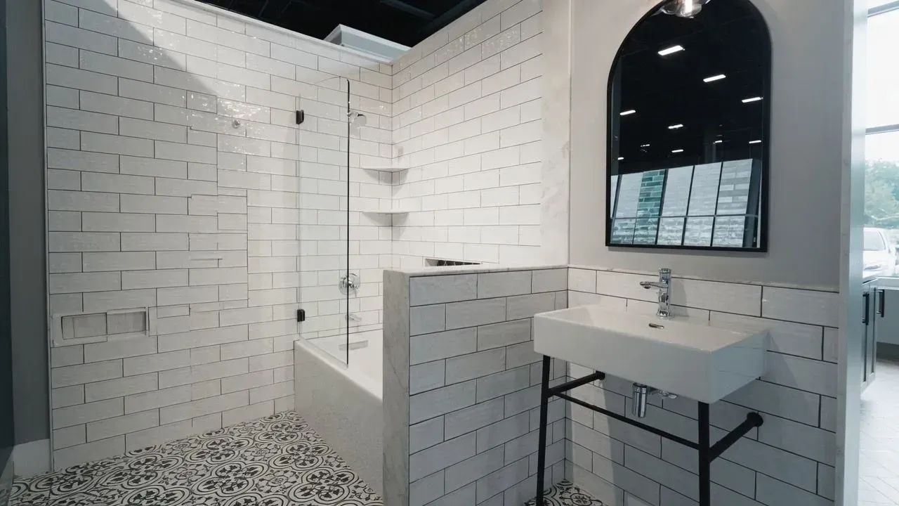 Modern bathroom with white subway-tile walls, walk-in shower, black floor, and wall-mounted sink with mirror