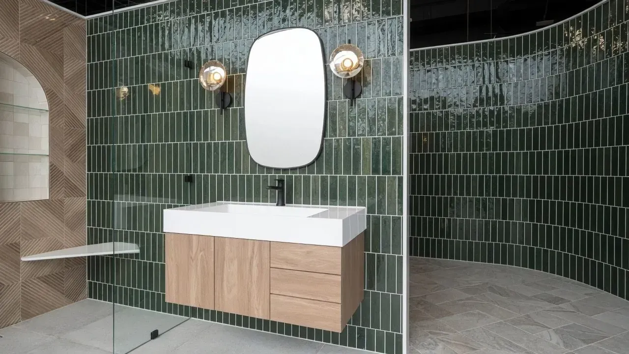 Modern bathroom with green tiled curved walls, white sink vanity, mirror, and shower area
