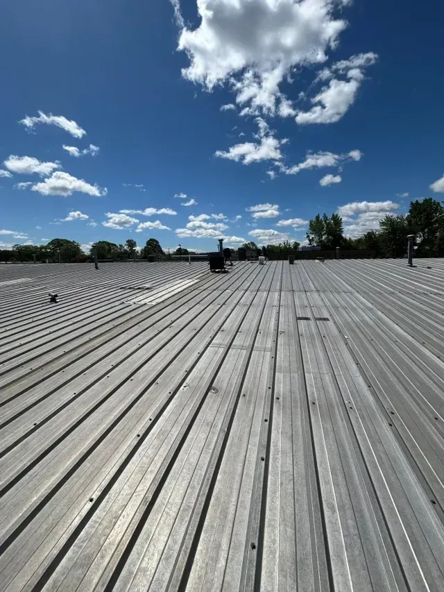 Rows of white solar panels stretching into the distance under a bright blue sky with scattered clouds.