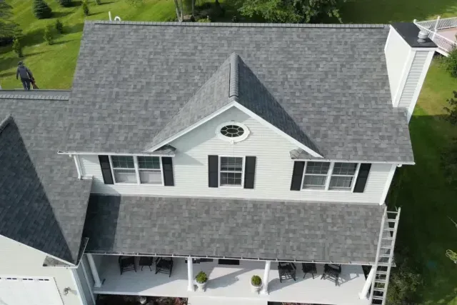 Aerial view of a gray two-story house with white trim and a front porch.